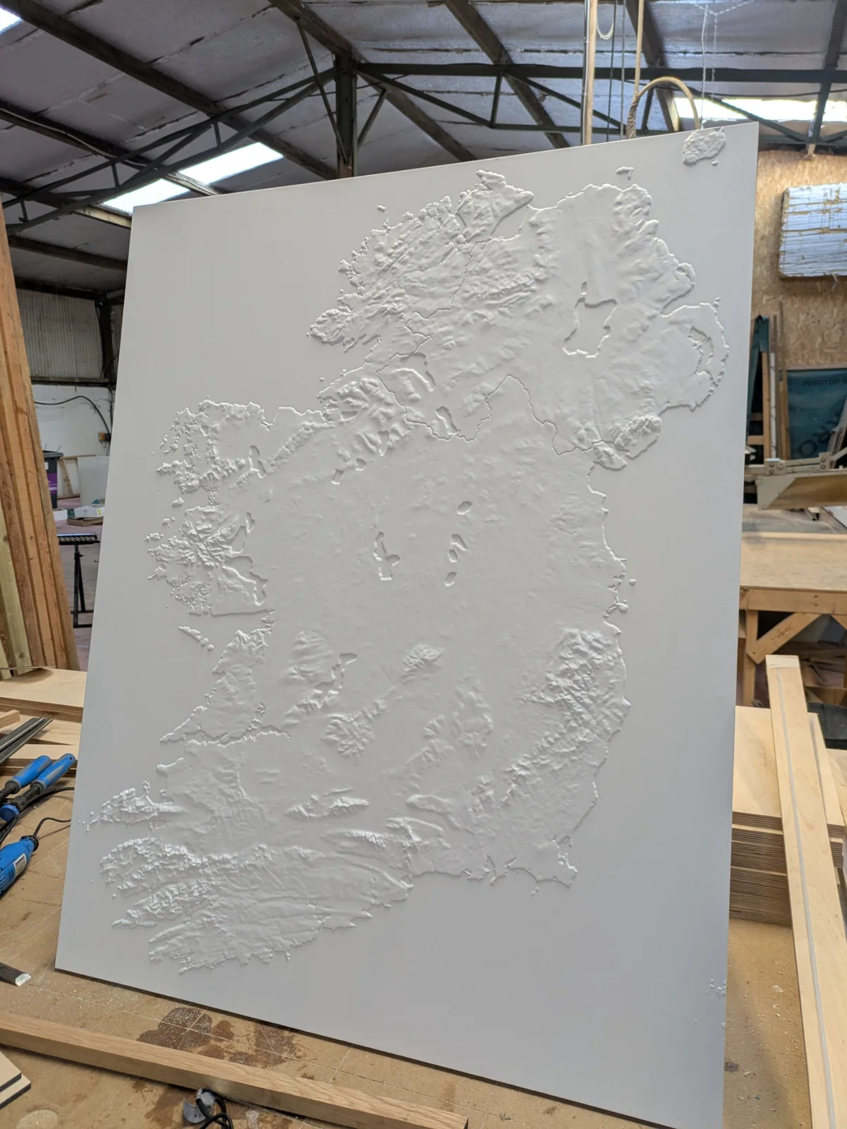 The full-island relief painted white and standing on the workshop bench