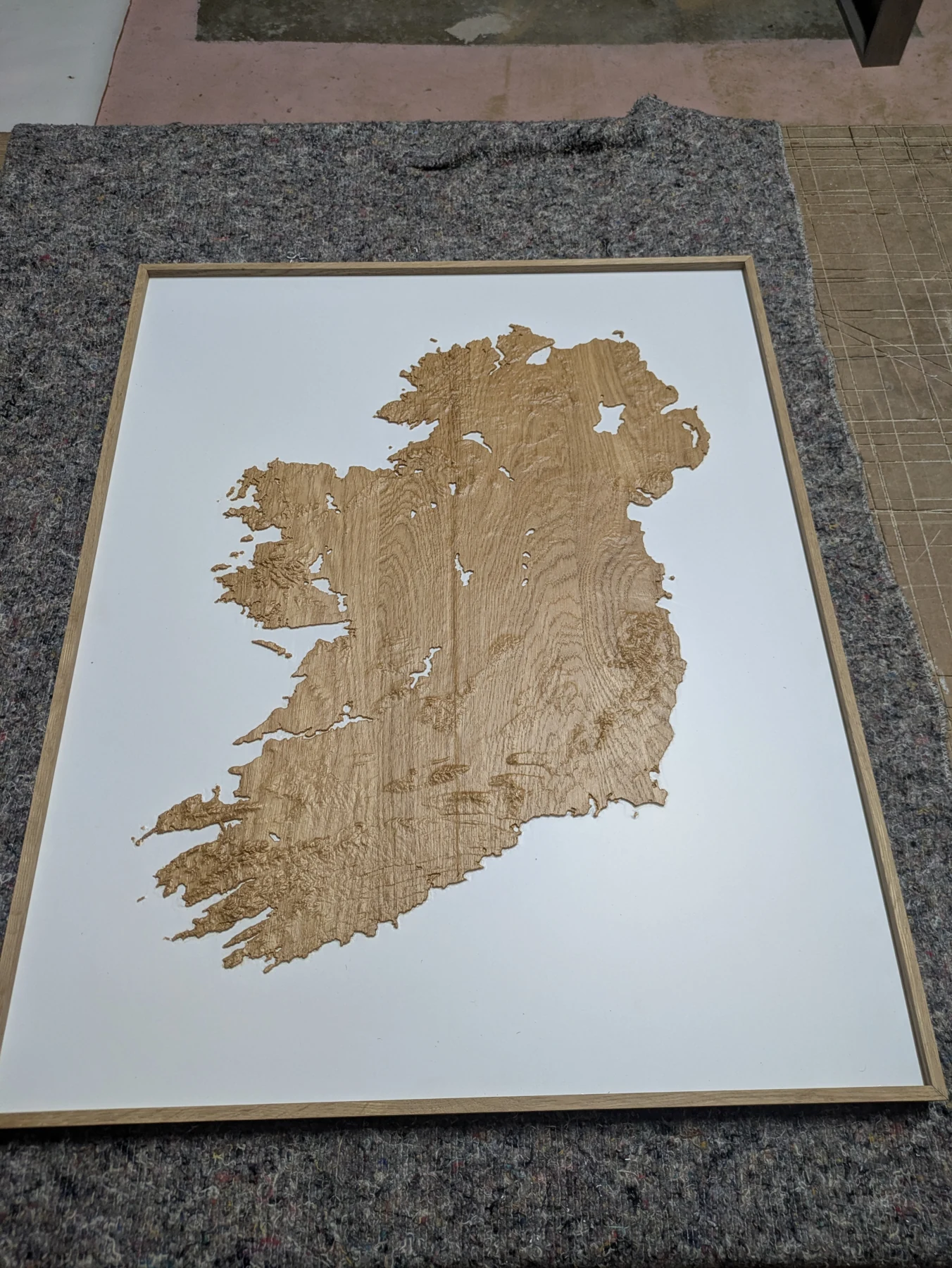 A framed oak model of the full island on a rectangular white backing