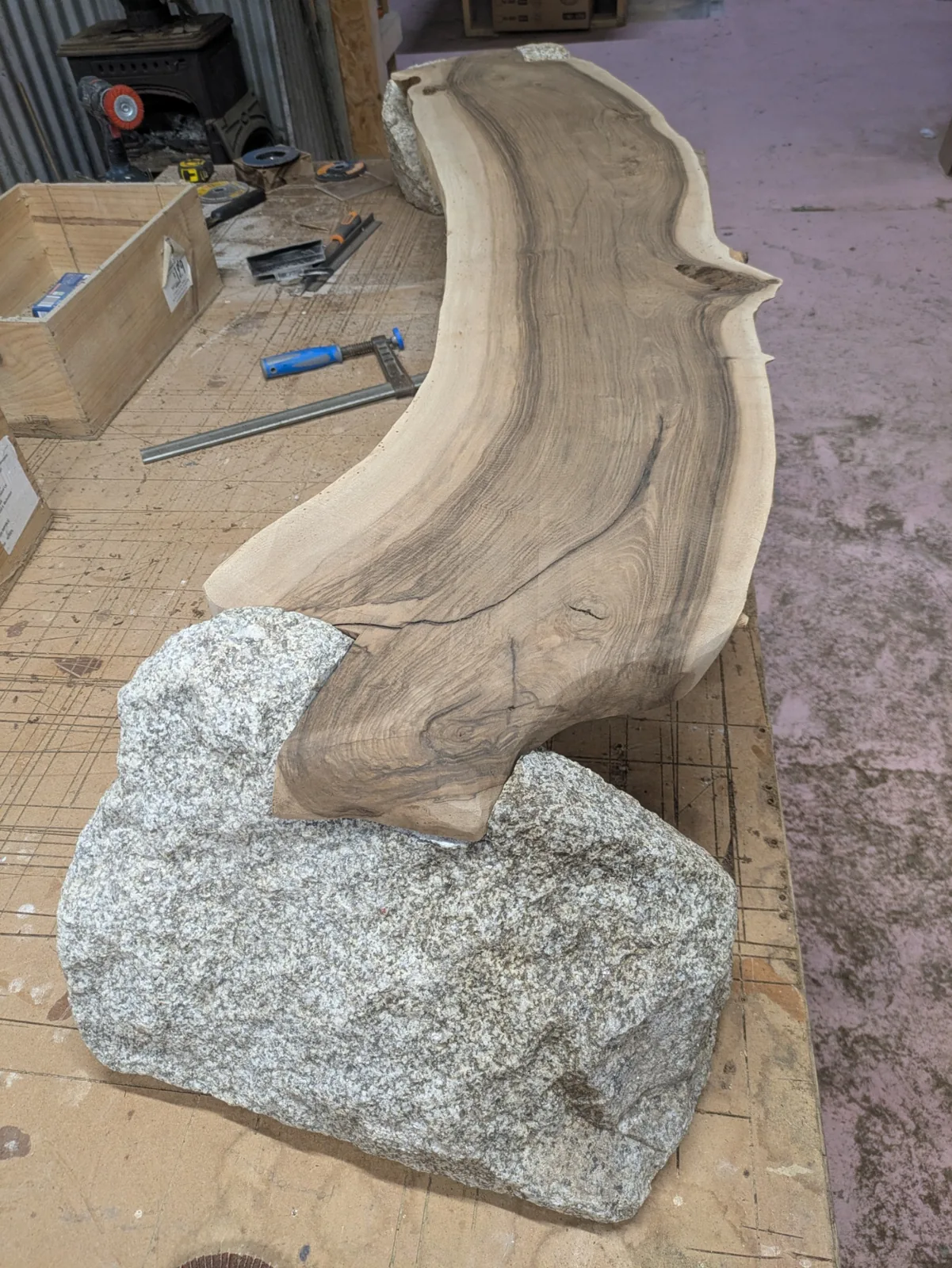 The shaped walnut meeting the granite in the assembled bench before finishing