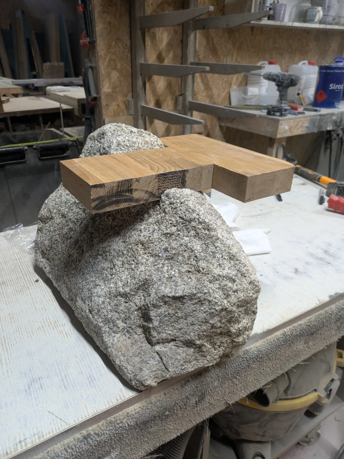 A wooden template resting on a granite stone to mark the joint